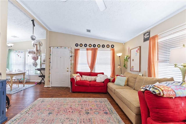 living area with dark wood-type flooring, lofted ceiling, visible vents, and a textured ceiling