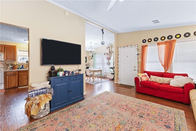 living room with dark wood finished floors, a notable chandelier, lofted ceiling, visible vents, and a textured ceiling