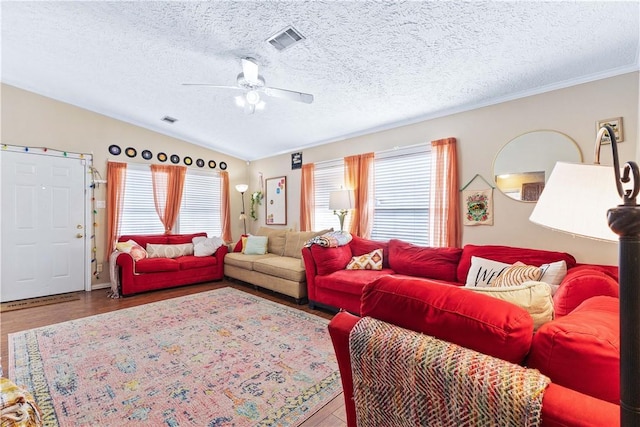 living room with lofted ceiling, a wealth of natural light, visible vents, and wood finished floors