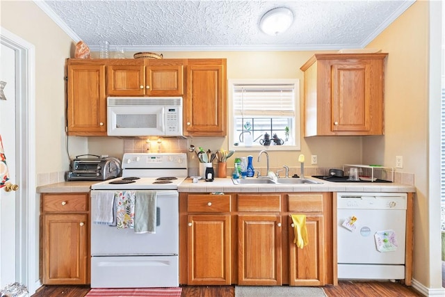 kitchen featuring a textured ceiling, white appliances, a sink, and crown molding