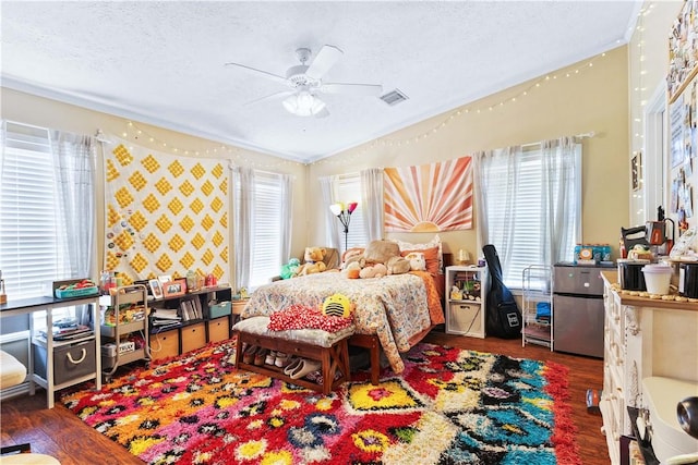 bedroom with dark wood-type flooring, visible vents, ceiling fan, and a textured ceiling