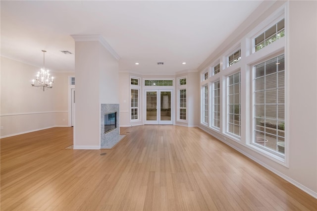 unfurnished living room featuring a chandelier, crown molding, a high end fireplace, and light hardwood / wood-style flooring