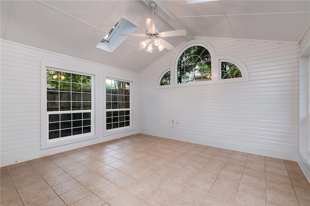 spare room featuring ceiling fan, light tile patterned floors, a wealth of natural light, and vaulted ceiling with skylight