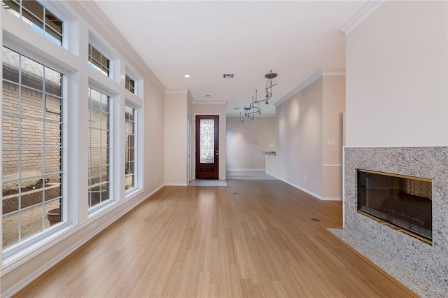 entryway featuring a fireplace, crown molding, light hardwood / wood-style flooring, and a healthy amount of sunlight