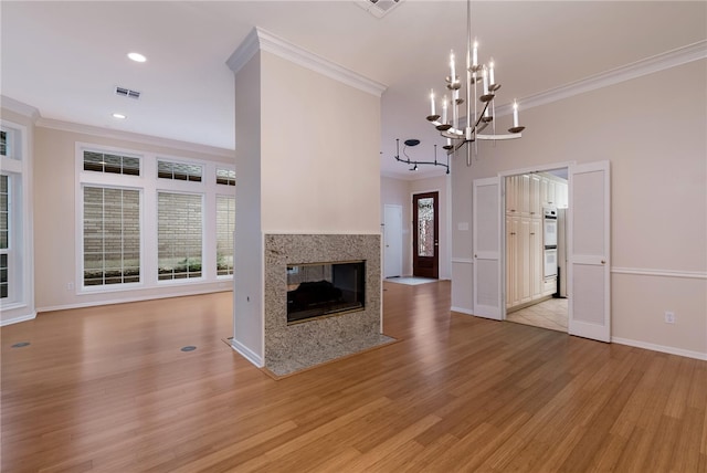 unfurnished living room with a chandelier, light wood-type flooring, a fireplace, and ornamental molding