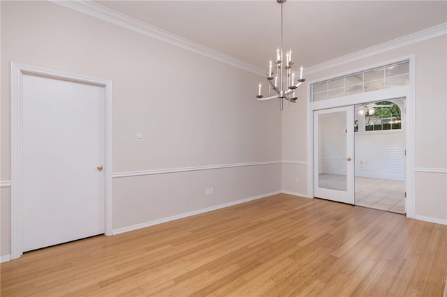 spare room featuring a chandelier, french doors, light hardwood / wood-style flooring, and crown molding