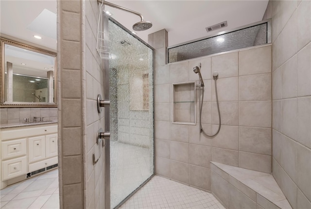 bathroom featuring tile patterned flooring, vanity, a tile shower, and tile walls