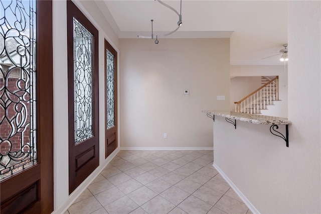 tiled entryway featuring ceiling fan and crown molding