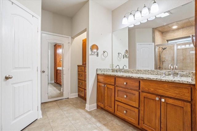 bathroom with tile patterned flooring, a sink, a shower stall, and double vanity