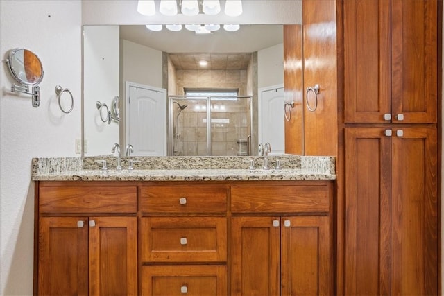 full bath featuring double vanity, a sink, and a shower stall