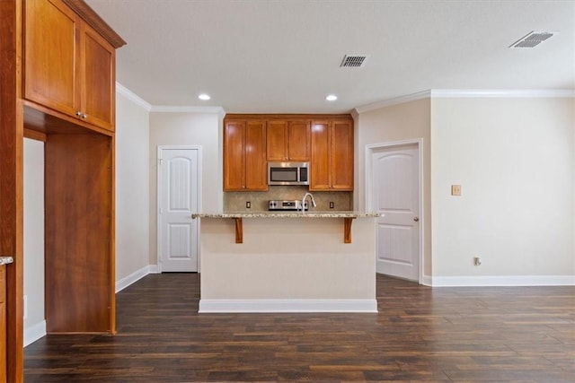 kitchen featuring dark wood finished floors, tasteful backsplash, stainless steel microwave, light stone countertops, and baseboards