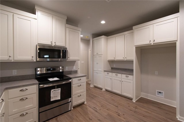 kitchen with dark hardwood / wood-style floors, stainless steel appliances, and white cabinets