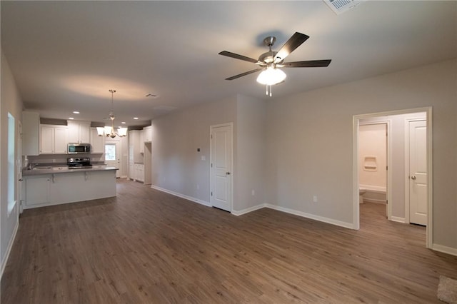 unfurnished living room featuring dark hardwood / wood-style flooring and ceiling fan with notable chandelier