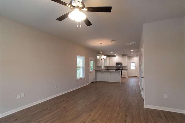 unfurnished living room featuring ceiling fan with notable chandelier and dark hardwood / wood-style floors