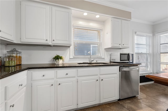 kitchen featuring ornamental molding, a sink, stainless steel appliances, dark stone counters, and white cabinets