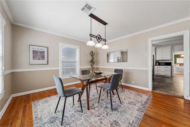 dining area with visible vents, baseboards, wood finished floors, and ornamental molding