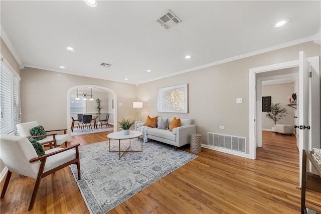 living area featuring arched walkways, visible vents, and light wood-type flooring