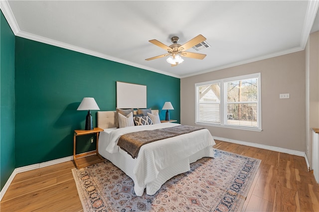 bedroom with a ceiling fan, crown molding, baseboards, and wood finished floors