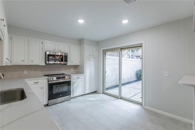 kitchen featuring white cabinets, sink, decorative backsplash, light stone countertops, and appliances with stainless steel finishes