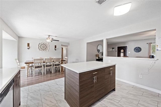 kitchen featuring ceiling fan, stainless steel dishwasher, dark brown cabinetry, and a kitchen island