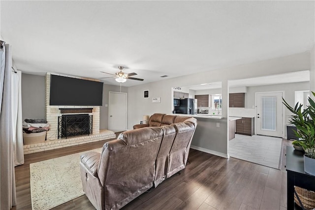 living room featuring dark wood-type flooring, ceiling fan, and a fireplace