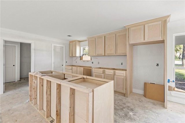 kitchen featuring light brown cabinetry, a center island, crown molding, and a healthy amount of sunlight