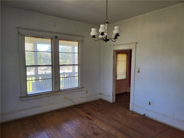 unfurnished dining area with dark hardwood / wood-style flooring and a chandelier