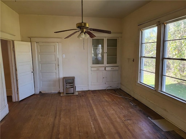 unfurnished dining area featuring dark hardwood / wood-style flooring, heating unit, and ceiling fan