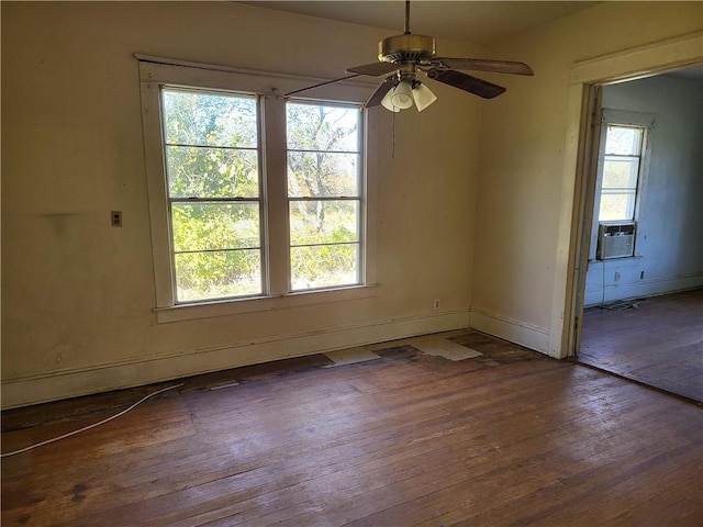 empty room featuring ceiling fan, cooling unit, and dark hardwood / wood-style flooring