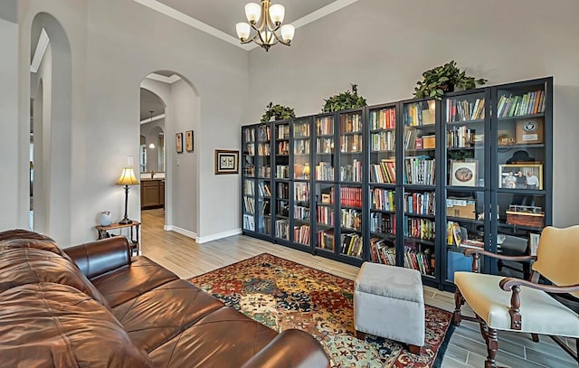 living area featuring wood-type flooring, crown molding, and a notable chandelier