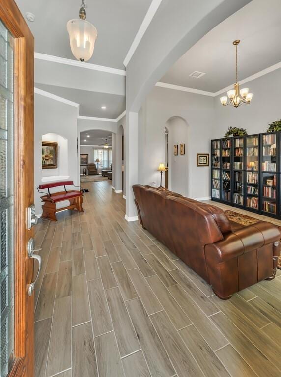 living room with a notable chandelier, light hardwood / wood-style floors, and crown molding