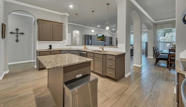 kitchen featuring sink, hanging light fixtures, kitchen peninsula, light wood-type flooring, and ornamental molding