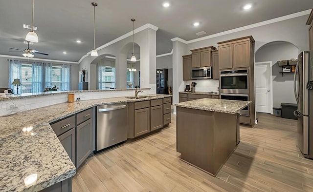 kitchen featuring light wood-type flooring, stainless steel appliances, ceiling fan, pendant lighting, and a kitchen island