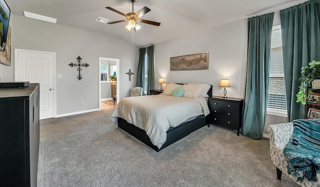 carpeted bedroom with ceiling fan, ensuite bathroom, and vaulted ceiling