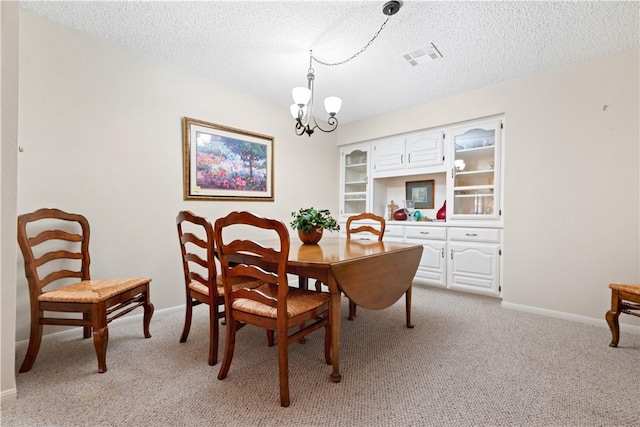 carpeted dining room featuring a notable chandelier and a textured ceiling