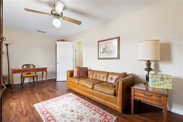 living room with ceiling fan, dark hardwood / wood-style floors, and a textured ceiling