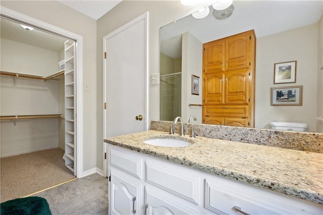 bathroom with walk in shower, toilet, a textured ceiling, vanity, and tile patterned flooring