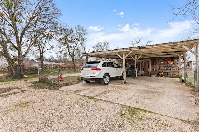 view of car parking with a carport, driveway, and fence