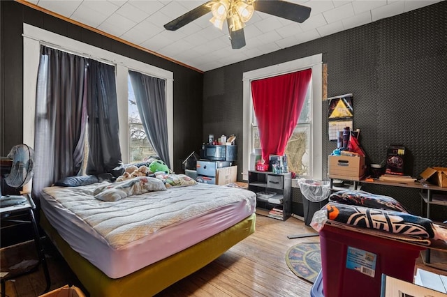 bedroom featuring wallpapered walls, ceiling fan, and wood-type flooring