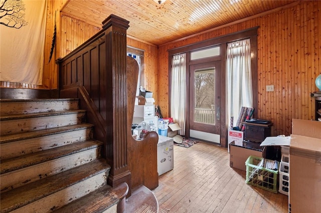 entryway featuring wood walls, wooden ceiling, stairs, and light wood-style floors