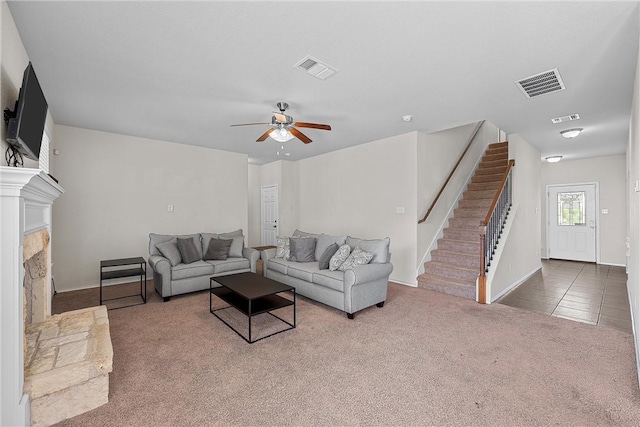 living room with carpet, a stone fireplace, and ceiling fan