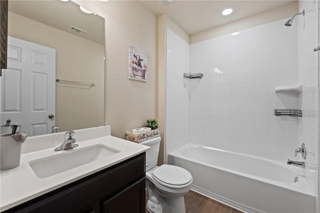 bathroom with toilet, wood finished floors, vanity, visible vents, and washtub / shower combination