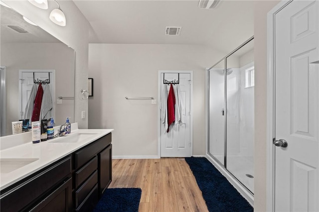 bathroom with visible vents, a sink, a shower stall, and wood finished floors