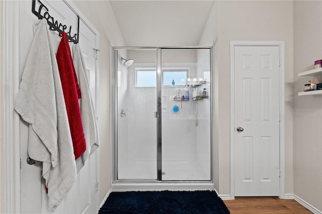 bathroom featuring a shower stall, baseboards, and wood finished floors