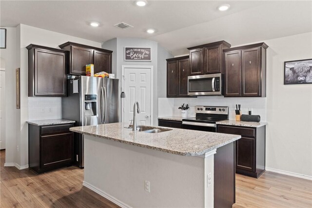 kitchen with stainless steel appliances, light wood finished floors, a sink, and dark brown cabinetry