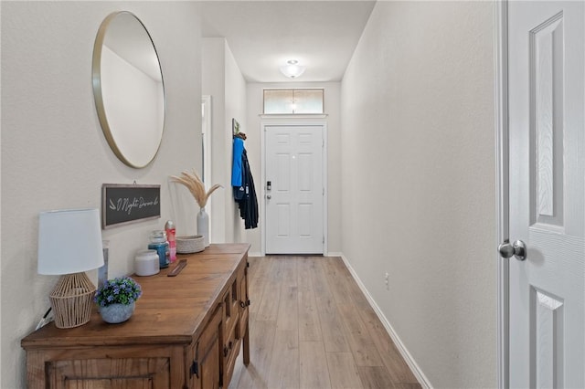 doorway featuring light wood finished floors and baseboards