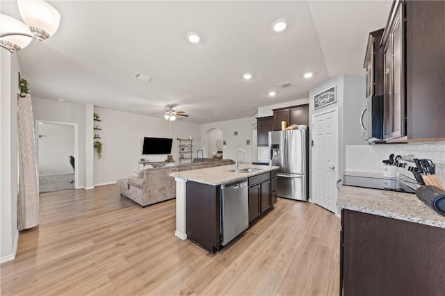 kitchen with ceiling fan, dark brown cabinetry, stainless steel appliances, light wood-style floors, and open floor plan