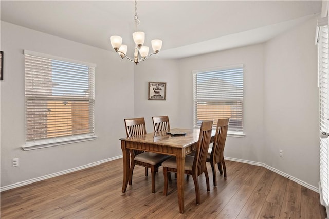 dining space with an inviting chandelier, wood finished floors, and baseboards