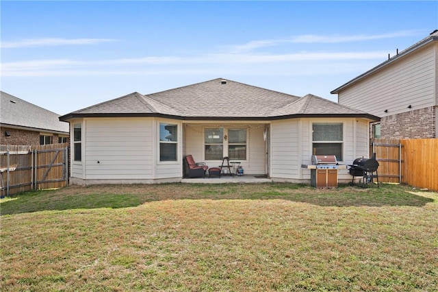 rear view of house featuring a yard, a fenced backyard, roof with shingles, and a patio