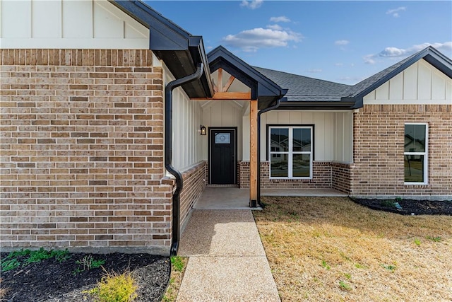 entrance to property featuring brick siding, board and batten siding, and roof with shingles